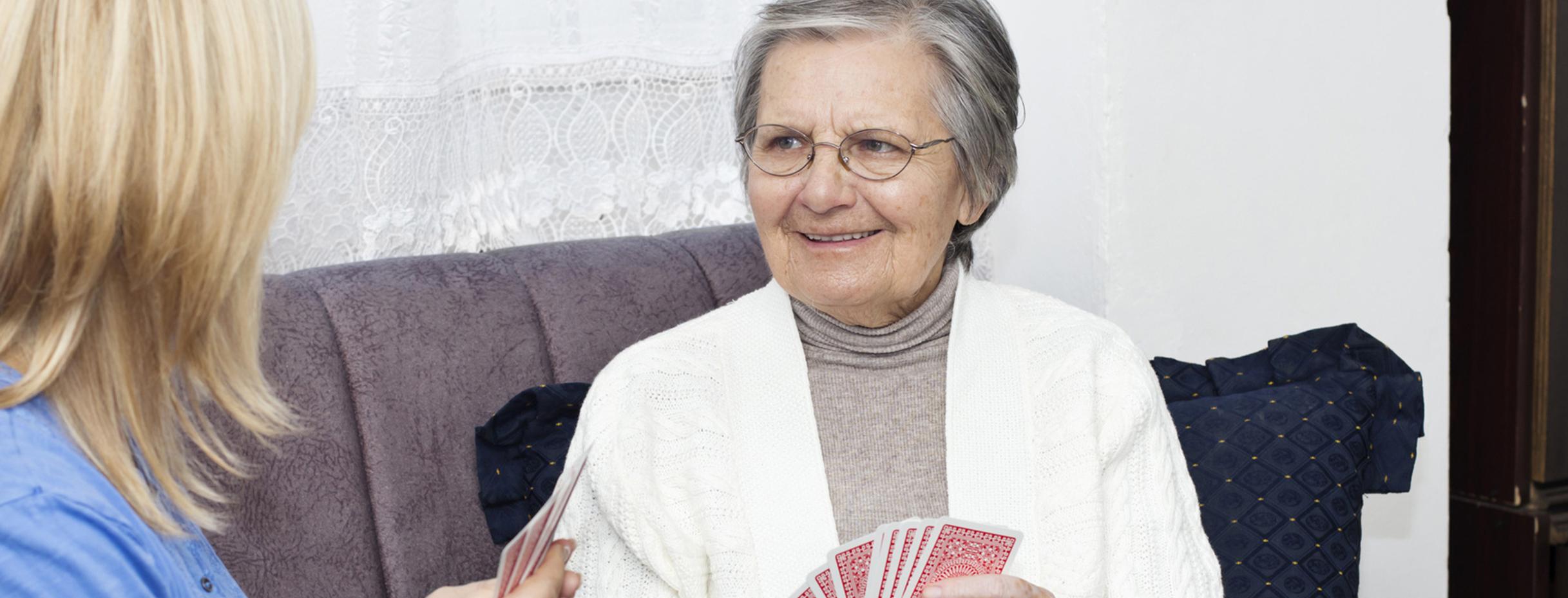 Seniorin und junge Frau spielen Karten