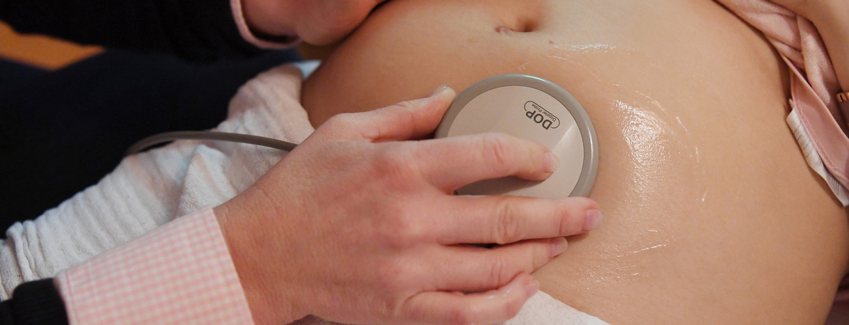 Eine Hebamme hört mit einem CTG die Herztöne eines Babys ab.