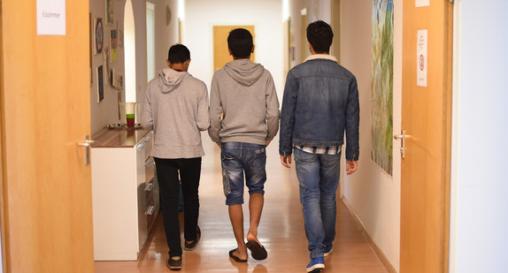 Unbegleitete minderjährige Flüchtlinge gehen in einem Kinder- und Jugendhilfezentrum einen Flur entlang.