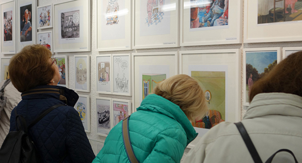 Ältere Frauen besuchen Ausstellung mit Karikaturen