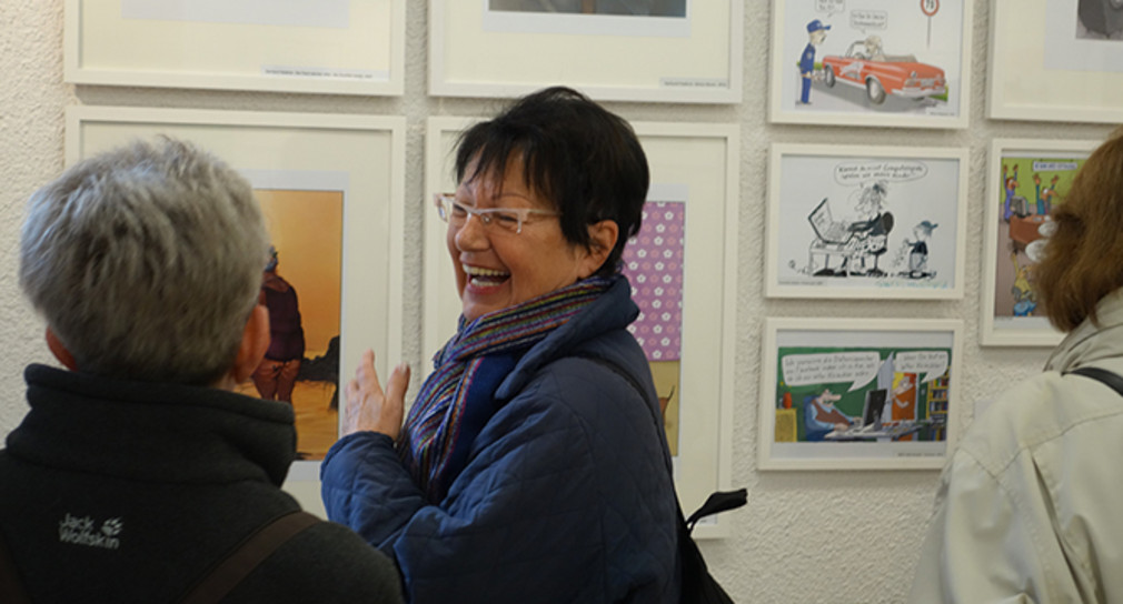 Lachende Frau vor ausgestellten Karikaturen