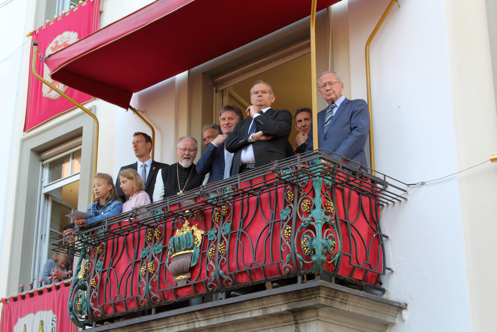 Sozialminister Manne Lucha steht mit weiteren Zuschauern auf dem Rathausbalkon der Stadt Weingarten.