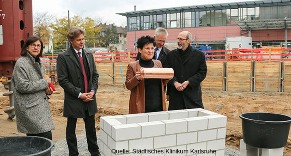 Gesundheitsministerin Katrin Altpeter legt die Zeitkapsel in den Mauerpfeiler.