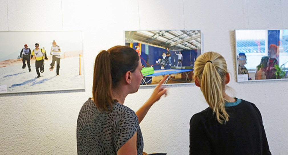 Zwei junge Frauen schauen Fotos an Wand an