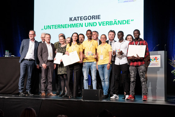 Gruppenbild aller Preisträger in der Kategorie „Unternehmen und Verbände“ auf der Bühne