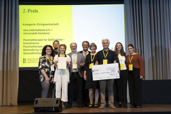 Preisverleihung Integrationspreis des Landes Baden-Württemberg Gruppenfoto der Preisträger von Platz 2 der Kategorie „Zivilgesellschaft“ mit Minister Manne Lucha auf Bühne.