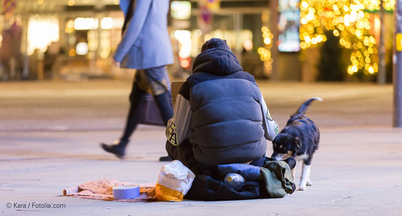 Obdachloser sitzt mit Hund in einer Fußgängerzone