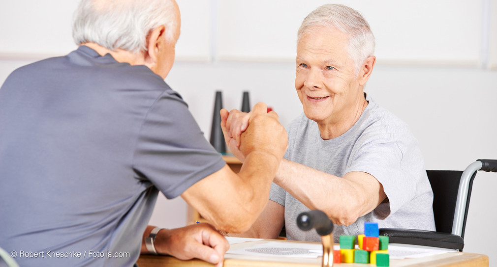 Zwei Senioren drücken sich die Hände im Pflegeheim