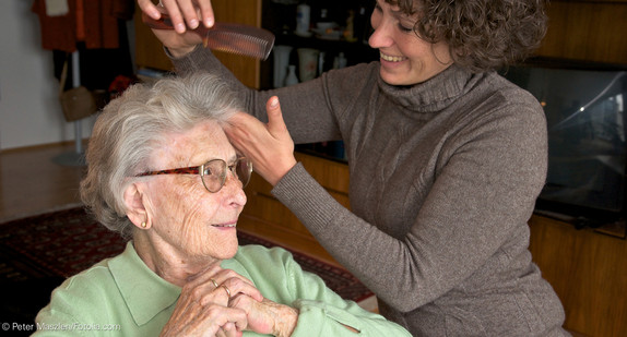 Frau kämmt älterer Frau die Haare