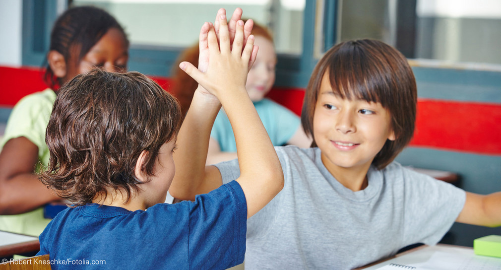 Zwei glückliche Schüler geben sich High Five im Unterricht