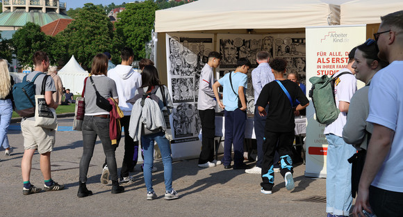 Besucherinnen und Besucher stehen an einem Infostand.