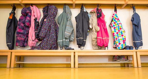 Jacken von Kindern hängen an der Garderobe einer Kindertagesstätte.