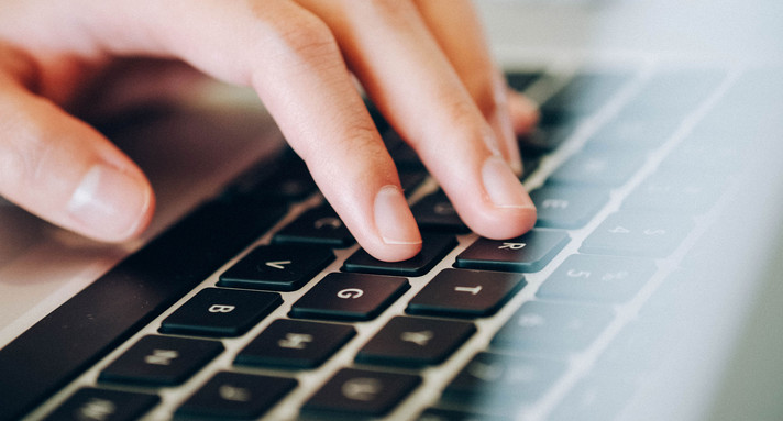 Hand tippt auf Laptop-Tastatur