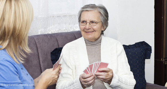 Seniorin und junge Frau spielen Karten