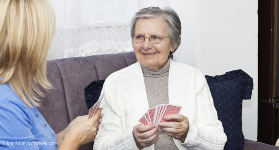 Seniorin und junge Frau spielen Karten