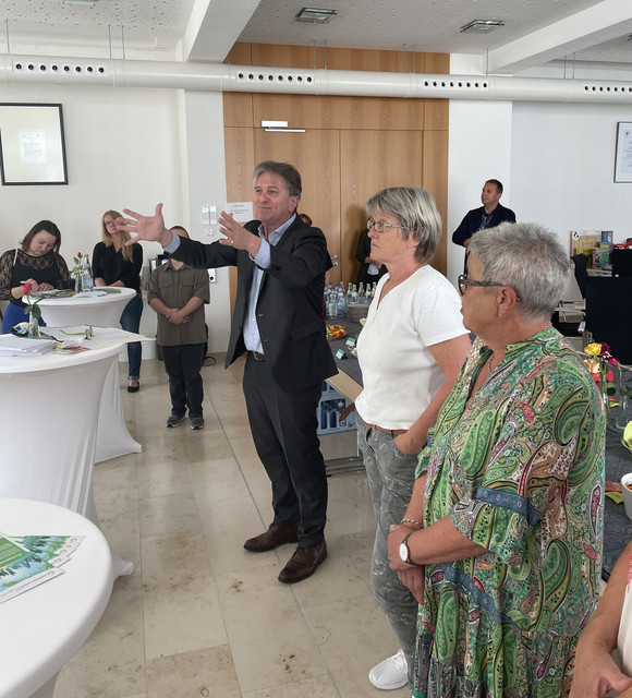 Minister Lucha steht im Mehrgenerationenhaus in Mengen mit weiteren Menschen zusammen.