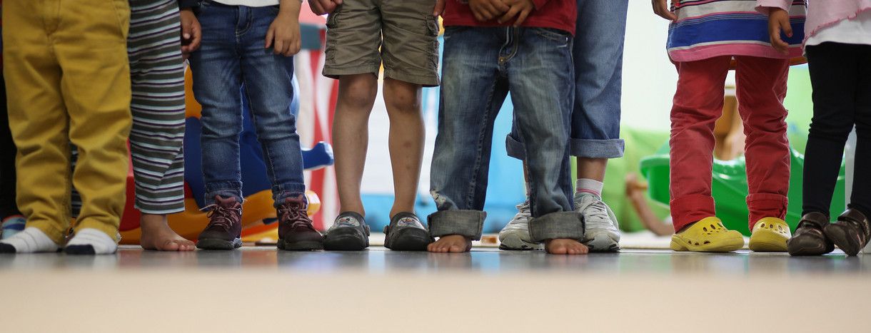 Mehrere Kinder stehen nebeneinander in einem Kindergarten. (Bild: © Christian Charisius/dpa)