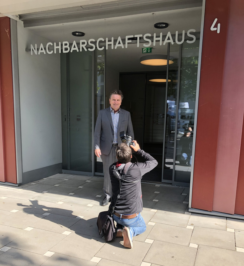 Minister Manne Lucha wird vor dem Eingang des Nachbarschaftshauses Scharnhauser Park fotografiert.