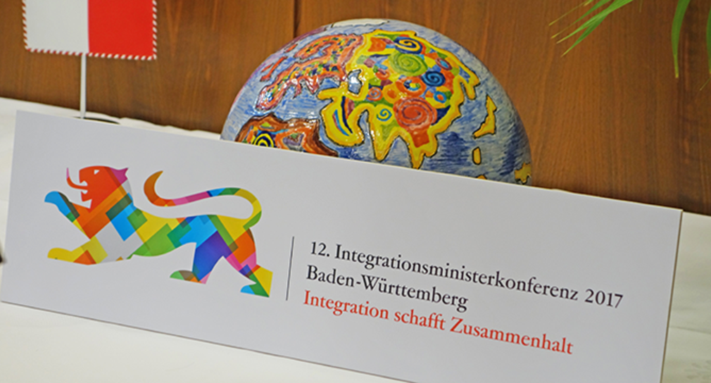 Platte mit aufgedrucktem Logo der IntMK 2017 lehnt an symbolischer Weltkugel