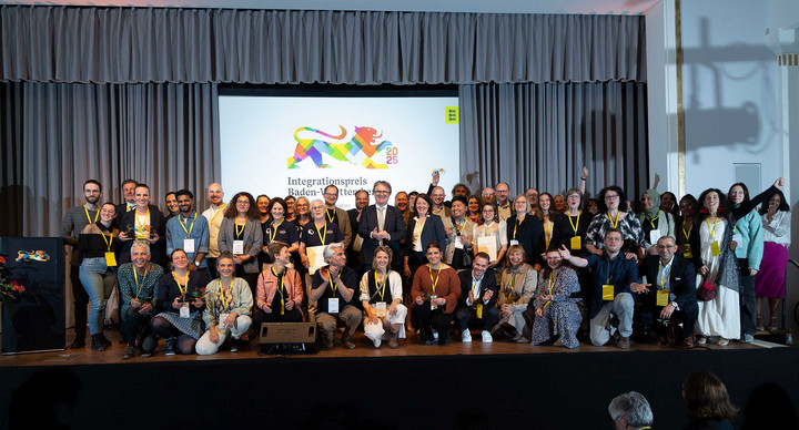 Gruppenfoto aller Preisträger des Integrationspreises 2025 mit Minister Manne Lucha auf Bühne.