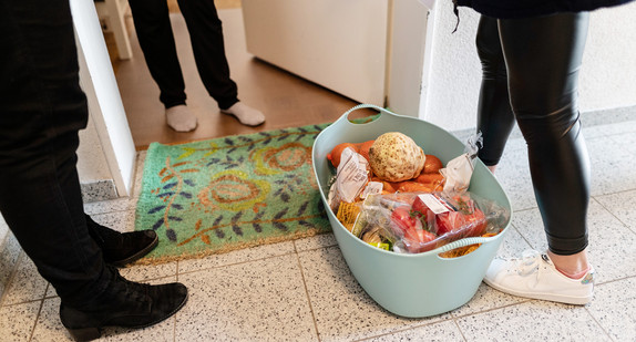 Mitarbeiterinnen des Malteser Hilfsdienstes stehen mit Lebensmitteln vor einer Haustür.