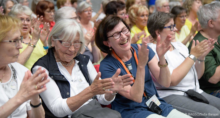 Lachende und klatschende Frauen in Veranstaltungspublikum.