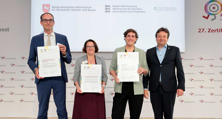 Gruppenfoto von drei Preisträgern auf Bühne der Verleihung des Zertifikats audit berufundfamilie +vielfalt in Berlin, darunter die Leiterin des Personal-Referats im Sozialministerium Baden-Württemberg,  Dr. Johanna Kemper.