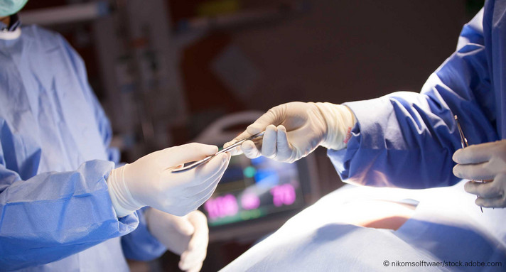 Person überreicht Skalpell an andere Person in Operationssaal.