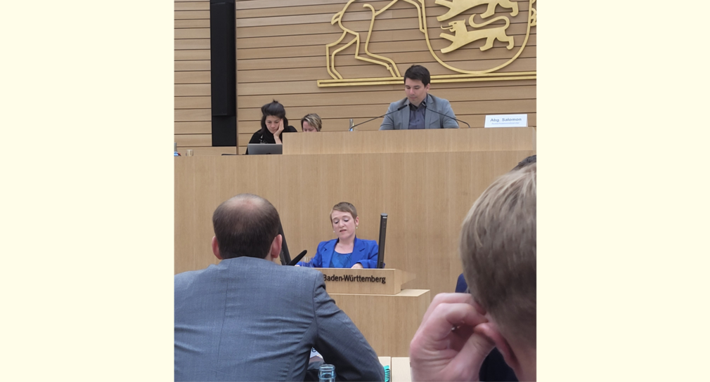 Simone Fischer spricht im Landtag von Baden-Württemberg vor zuhörenden Abgeordneten. Simone Fischer steht am Rednerpult. Hinter ihr sitzen der Vorsitzende der Enquetekommission, Alexander Salomon (Grüne) sowie zwei Protokollantinnen.