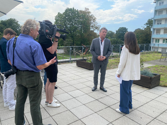 Gefilmt von einem Kameramann beantwortet Minister Lucha auf der Klinikterrasse in Mannheim Fragen der anwesenden Medienvertreter.