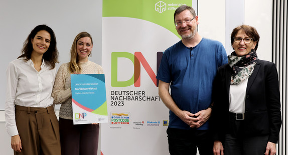 Gruppenfoto vor nebenan.de-Rollup: Katharina Roth, nebenan.de Stiftung, Rebekka Stutzman und René Richter vom Landessiegerprojekt Baden-Württemberg Gartenwerk!statt und Dr. Ute Leidig, Staatssekretärin im Ministerium für Soziales, Gesundheit und Integration.