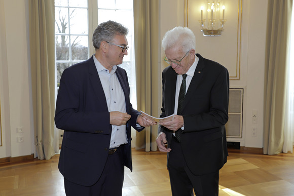 Dr. Dieter Salomon (links), Vorsitzender des Normenkontrollrats Baden-Württemberg, überreicht Ministerpräsident Winfried Kretschmann (rechts) den Tätigkeitsbericht für das Jahr 2025.