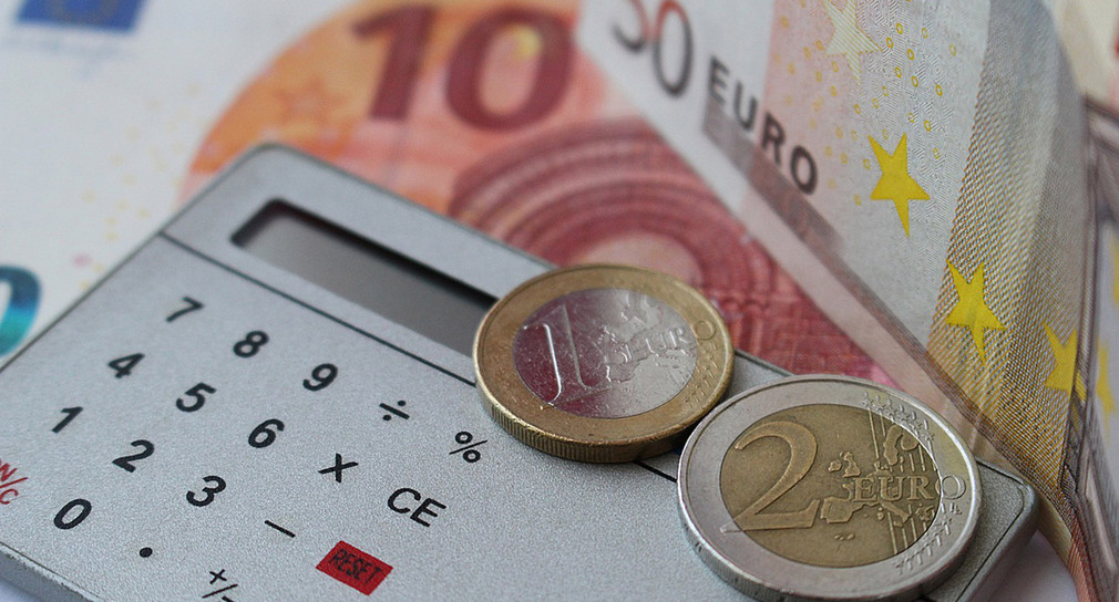 Euromünzen liegen auf Taschenrechner