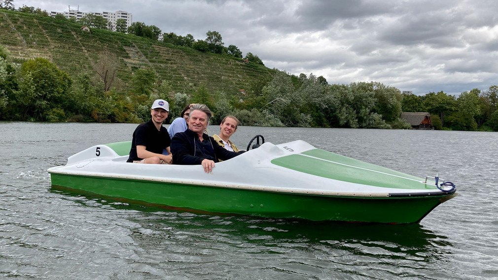 Minister Lucha fährt zusammen mit drei Jugendgemeinderäten in einem Tretboot über den Max-Eyth-See in Stuttgart.