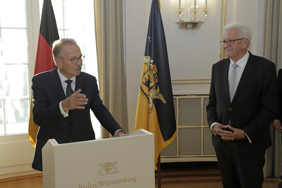 Wirtschaft Kretschmann ehrt Franz Fehrenbach Franz Fehrenbach (links) und Ministerpräsident Winfried Kretschmann (rechts) stehen stehen im Runden Saal der Villa Reitzenstein vor Fahnen.