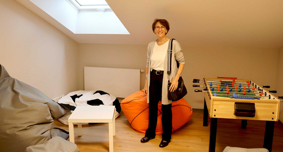 Staatssekretärin Dr. Ute Leidig steht in einem Zimmer neben einem Tischkicker und mehreren Sitzkissen.