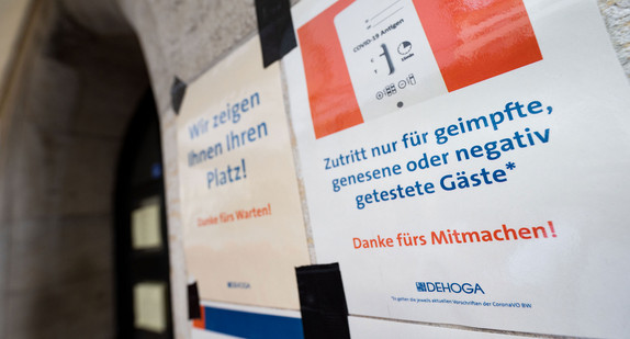 Zettel mit Aufschrift „Eintritt nur für geimpfte, genesene oder negativ getestete Gäste“ hängt neben anderen Hinweisen an der Tür eines Restaurants