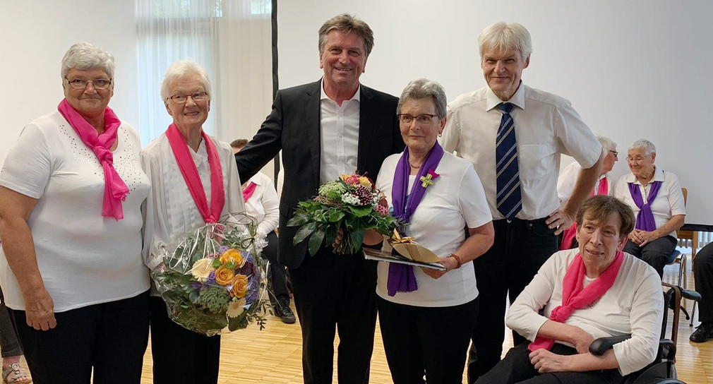 Minister Manne Lucha und Rangendingens Bürgermeister Johann Widmaier überreichen Blumen an Mitglieder des Generationentreff-Chors