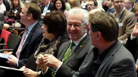 Minister Manne Lucha, Ministerpräsident Winfried Kretschmann und Staatsrätin Gisela Erler sitzen im Publikum