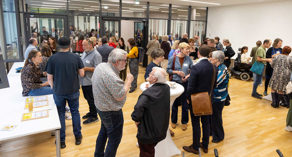 Personen stehen nach Veranstaltung in kleinen Gruppen zusammen und unterhalten sich.