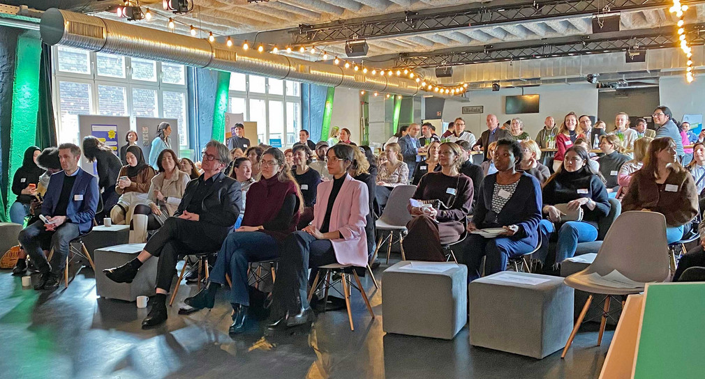 Publikum mit knapp 100 Personen bei einer Fachveranstaltung blickt Richtung Bühne.