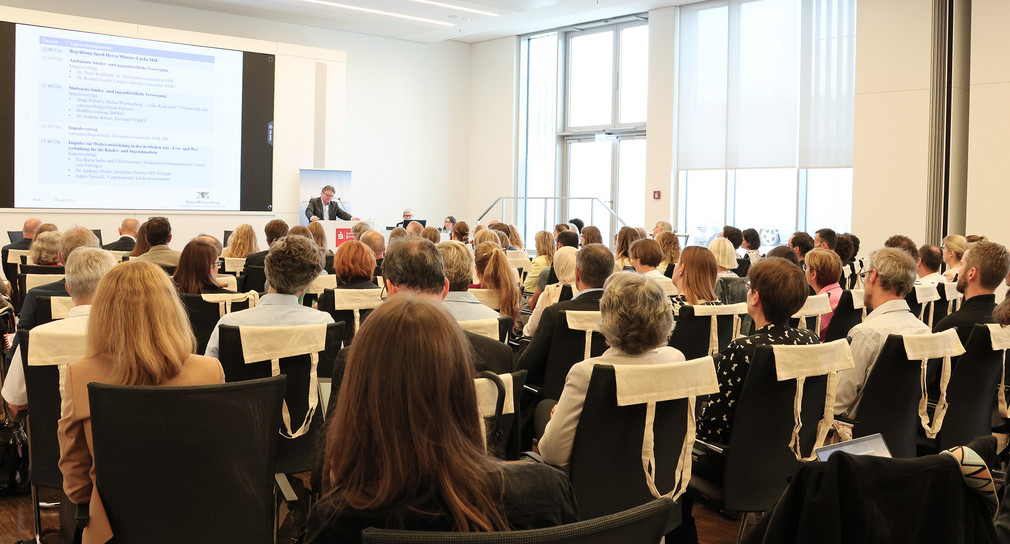 Minister Manne Lucha spricht vor Publikum auf dem Fachsymposium Kinder- und Jugendgesundheit am 25. Juli 2023 in Stuttgart