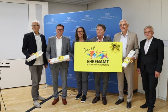 Gruppenfoto mit großer Ehrenamtskarte: Gerhard Rieger (Stadt Freiburg), Dr. Joachim Bläse (Landrat Ostalbkreis), Iris Mann (Bürgermeisterin der Stadt Ulm), Sozialminister Manne Lucha, Helmut Riegger (Landrat das Landkreises Calw), OB Michael Makurath (Vizepräsident des Städtetags Baden-Württemberg)