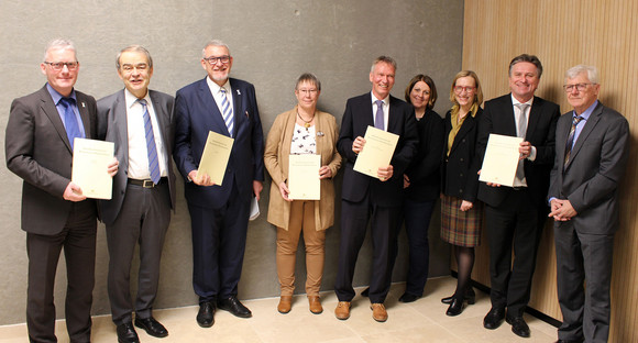 Gruppenbild: Mitglieder der Kommission Kinderschutz, darunter Minister Manne Lucha, halten Abschlussbericht in den Händen