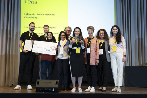 Preisverleihung Integrationspreis des Landes Baden-Württemberg Gruppenfoto der Preisträger von Platz 1 der Kategorie „Kommunen und Verwaltungen“ mit Minister Manne Lucha auf Bühne.
