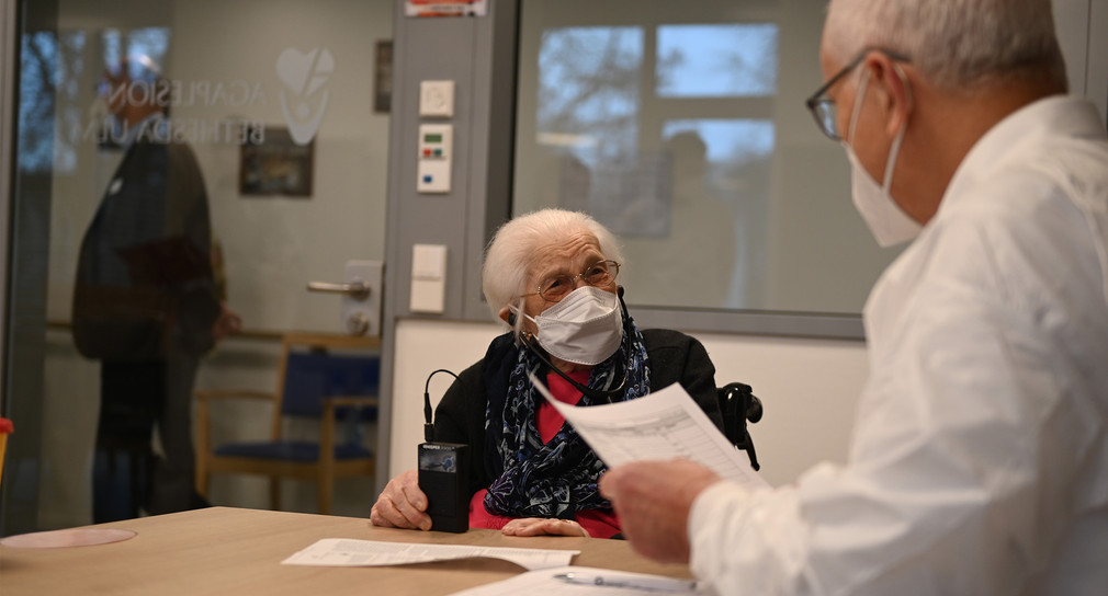 Der Arzt führt das Aufklärungsgespräch vor der Impfung mit der alten Dame