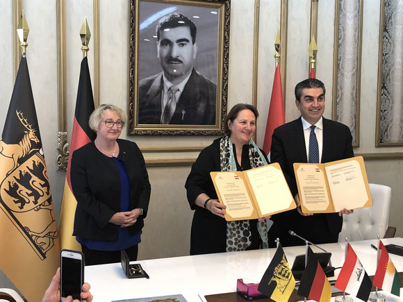Delegationsreise Besuch in der Autonomen Region Kurdistan-Irak Staatsministerin Theresa Schopper (M.) und der Gouverneur des Gouvernements Dohuk, Farhad Atrushi (r.), bei der Unterzeichnung eines Kooperationsabkommens im Bereich der humanitären Hilfe mit dem Land Baden-Württemberg, daneben Wissenschaftsministerin Theresia Bauer (l.) (Bild: Staatsministerium Baden-Württemberg)