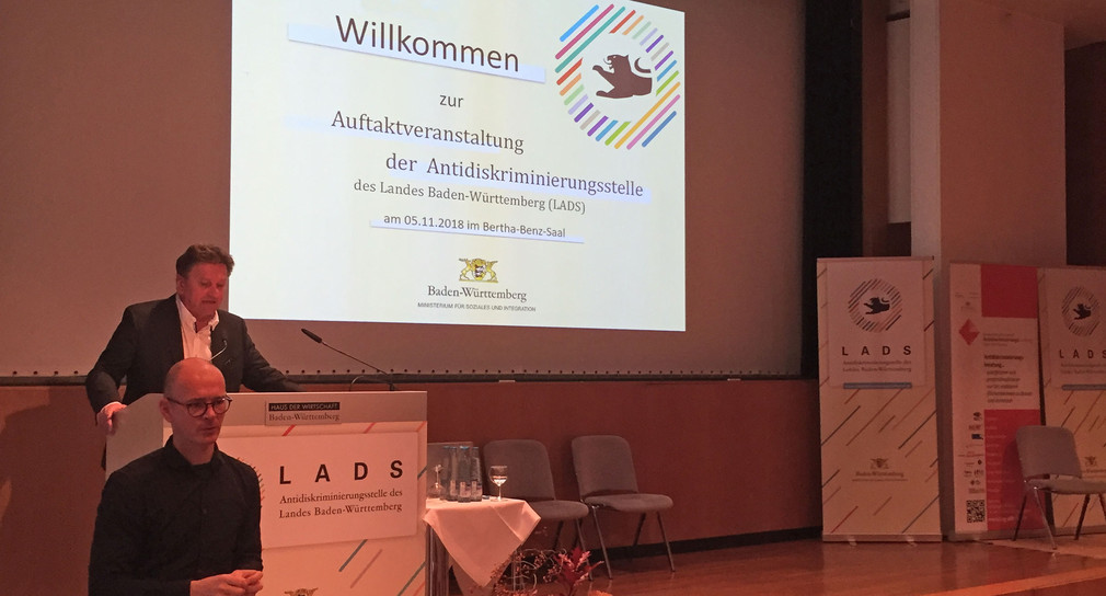 Minister Manne Lucha steht am Redepult auf der Eröffnungsveranstaltung der Antidiskriminierungsstelle des Landes Baden-Württemberg (LADS) (Bild: © Ministerium für Soziales und Integration Baden-Württemberg)