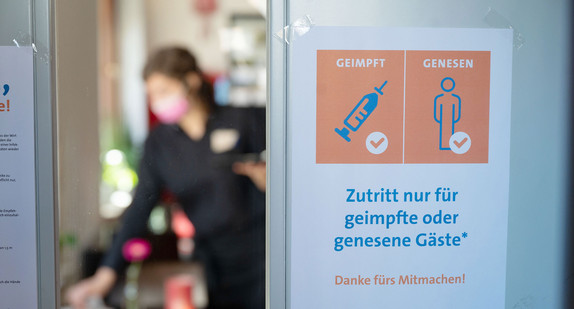 An der Eingangstür eines Restaurants hängt ein Schild mit der Aufschrift „Zutritt nur für geimpfte oder genesene Gäste“.