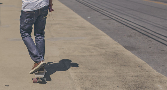 Junger Skateboarder auf Gehweg